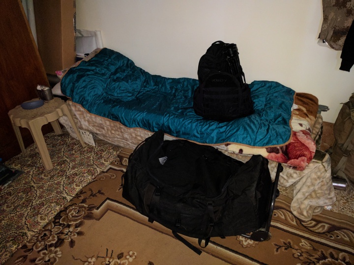Bunk with blanket and black bags.